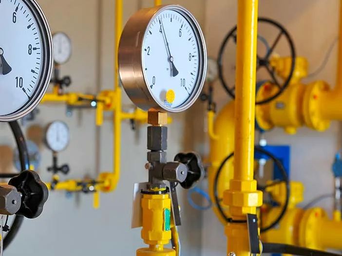 Central de gás com manômetros e tubulação amarela em sala técnica